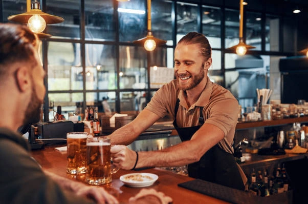 bartender serving two beers and smiling.