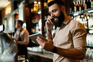 a smiling male bartender talking on the phone