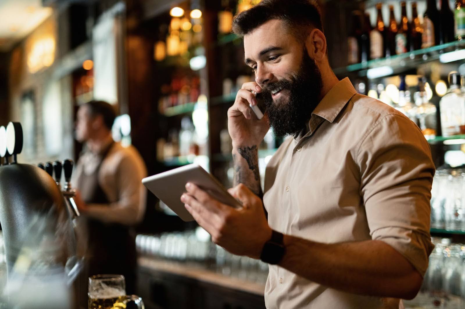 a smiling male bartender talking on the phone