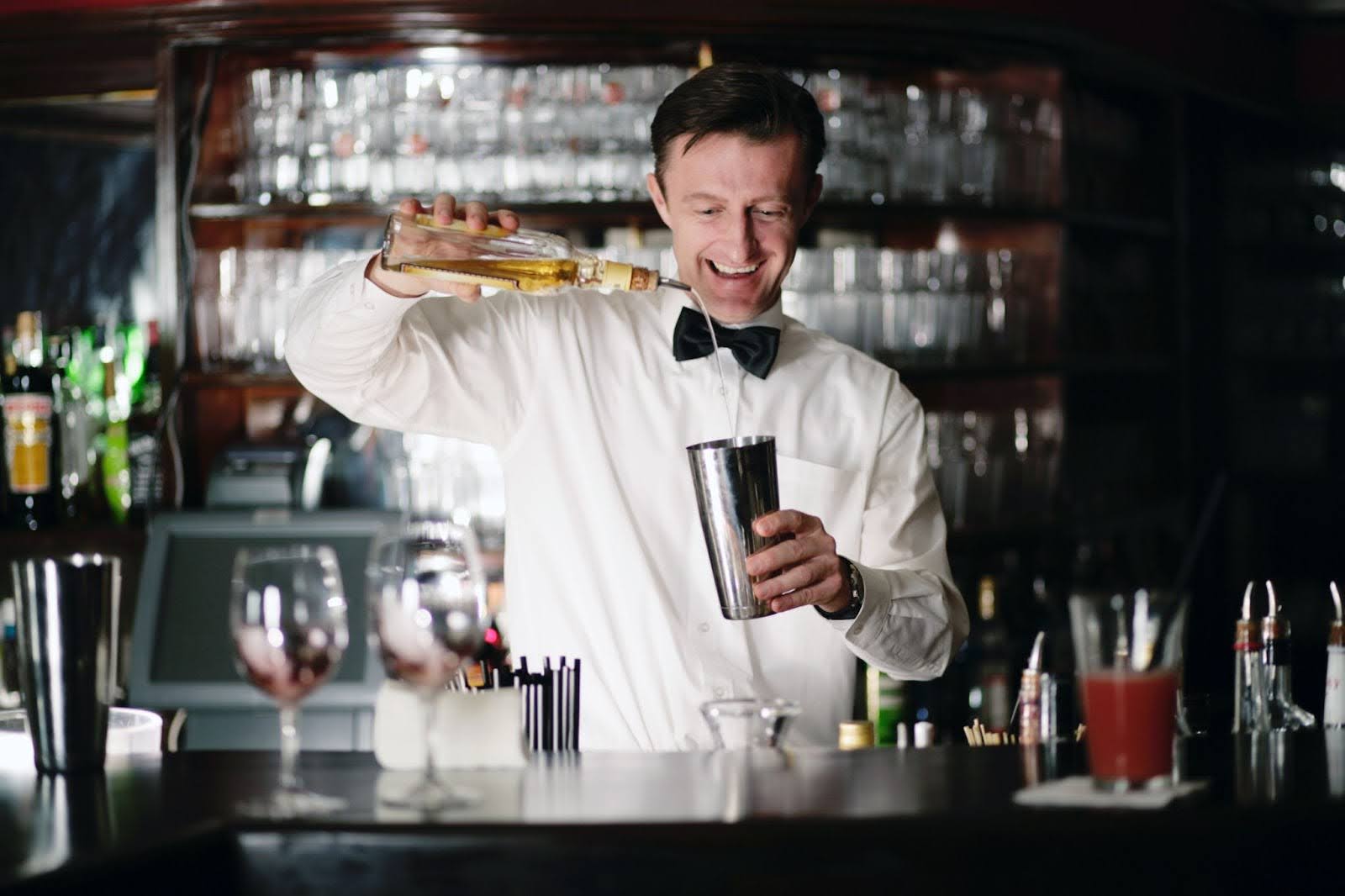 a bartender is practicing his cocktail-making skills behind the bar
