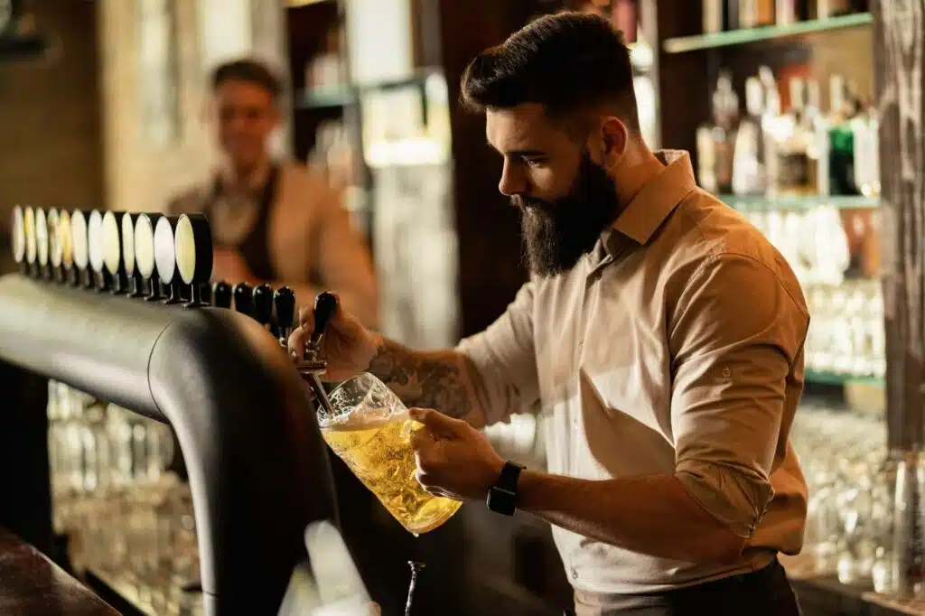 a bartender pouring draft beer from the tap