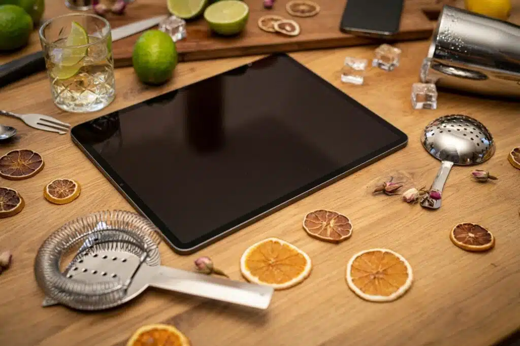 online bartending course with a tablet, a bartending kit, ingredients, and a glass on a wooden table