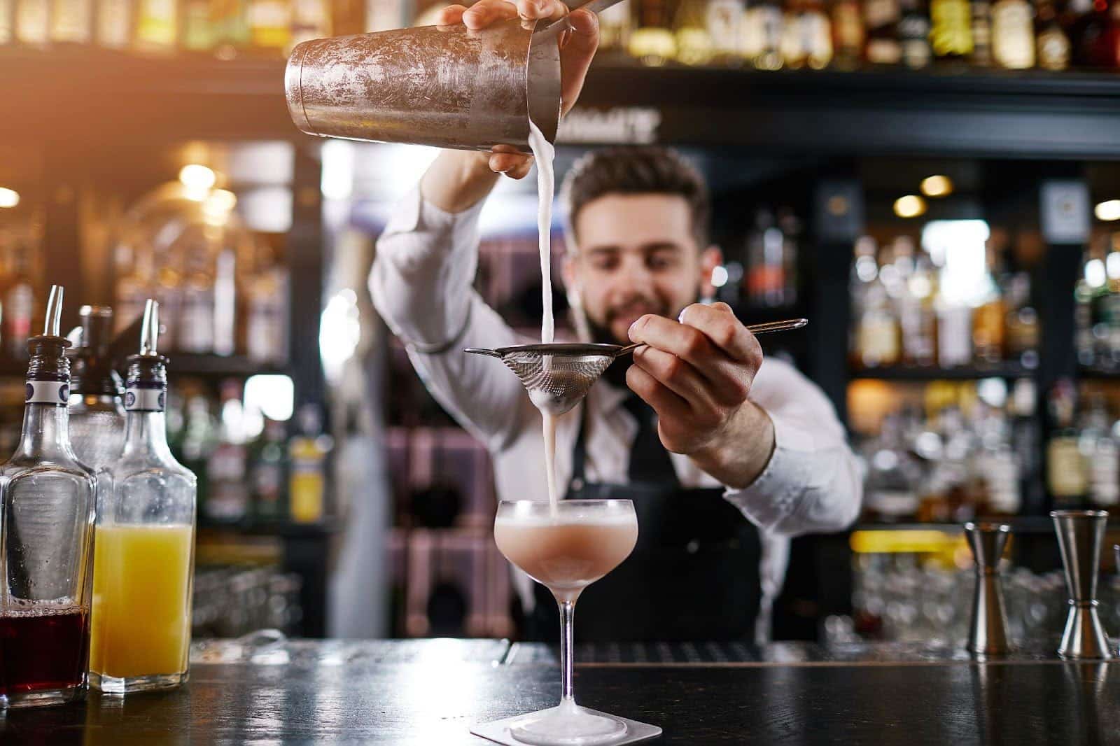 a professional bartender is making a cocktail drink