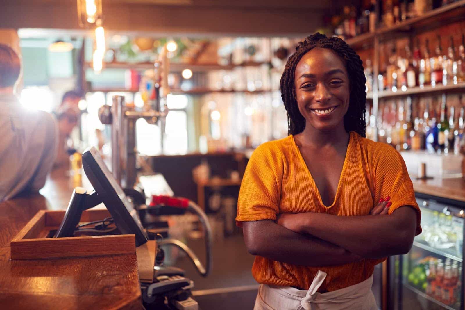 a smiling bartender working and standing behind the counter